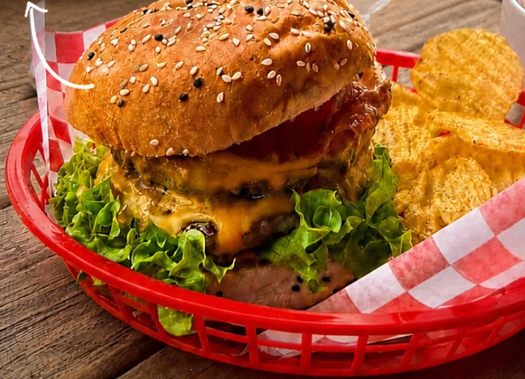 Hamburguesa doble con queso en canasta roja con papas onduladas
